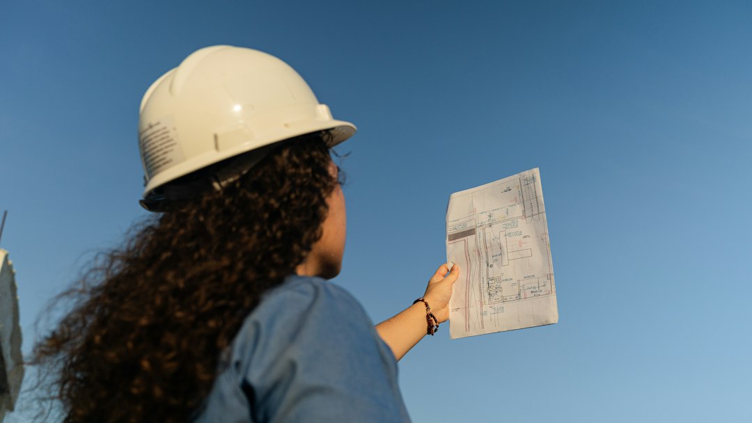 Builder in a hard hat reviewing plans on a residential job site