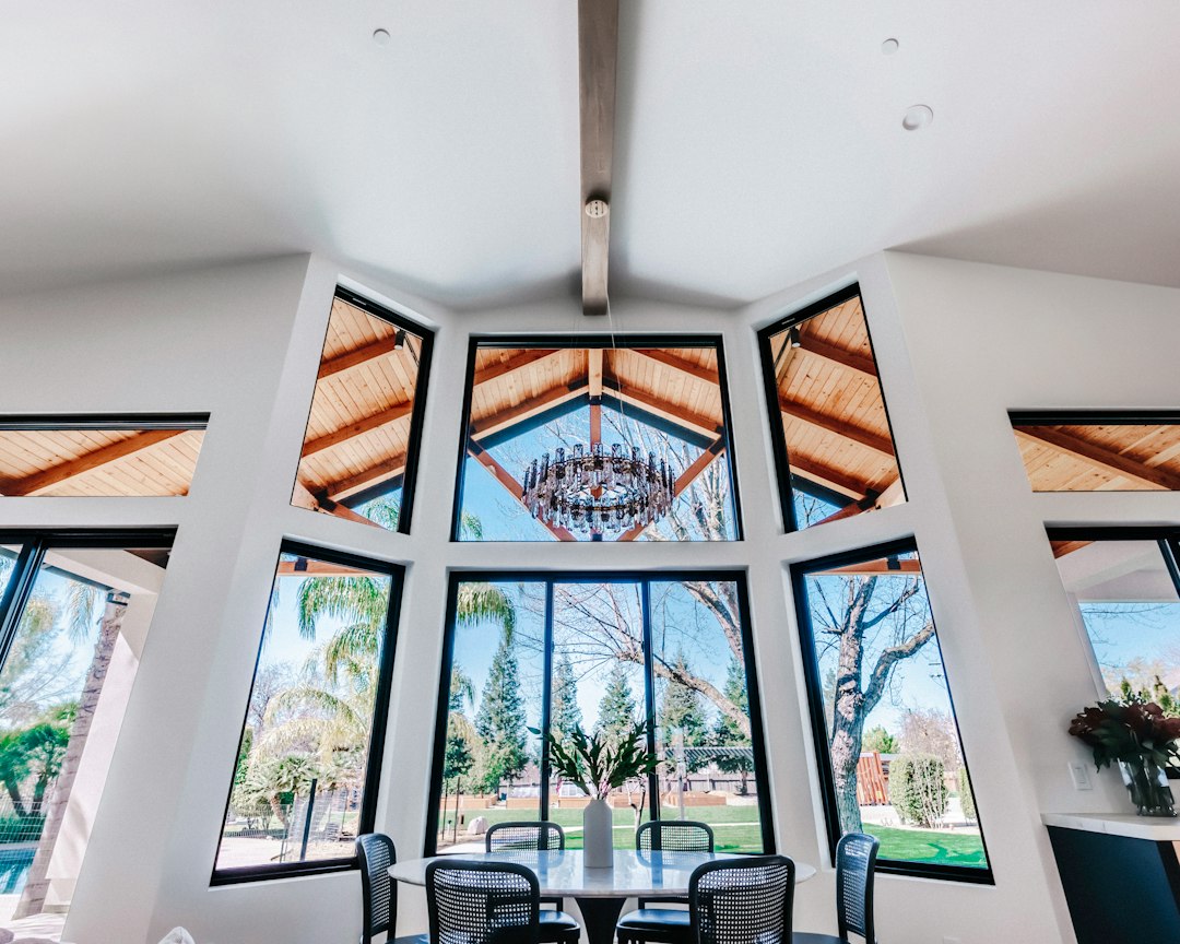 Custom home dining room with a vaulted ceiling, exposed wood beams and tall black-framed windows